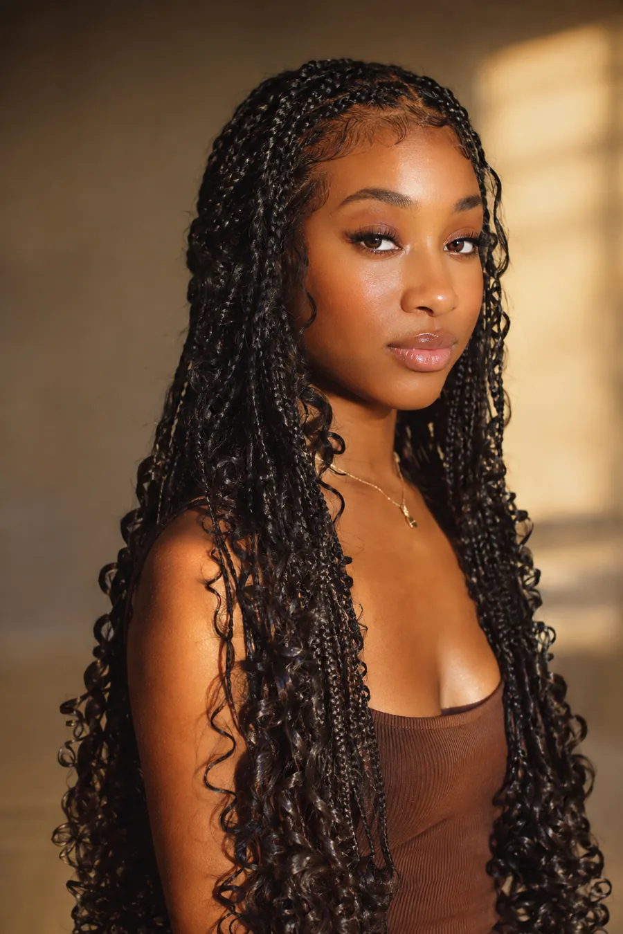 Woman with goddess knotless braids with curly ends in golden light